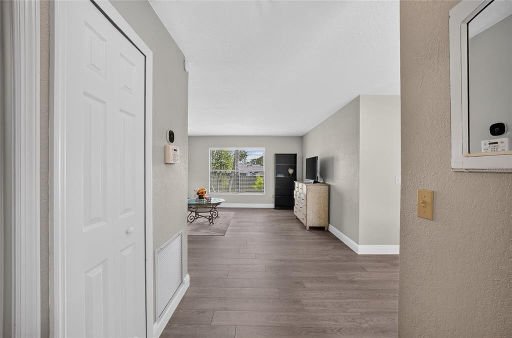 A view from a hallway into a living room with wood-look flooring and a window — 2495 E TIPTON DRIVE, DELTONA, FL