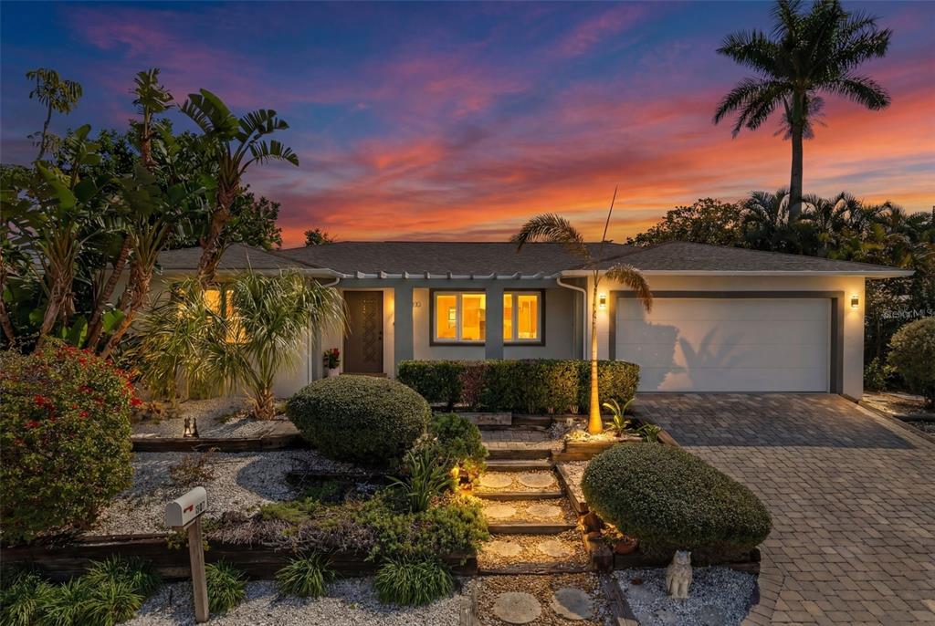 A single-story house with a paved driveway, landscaped front yard, and a sunset sky — 550 DE NARVAEZ DRIVE, LONGBOAT KEY, FL