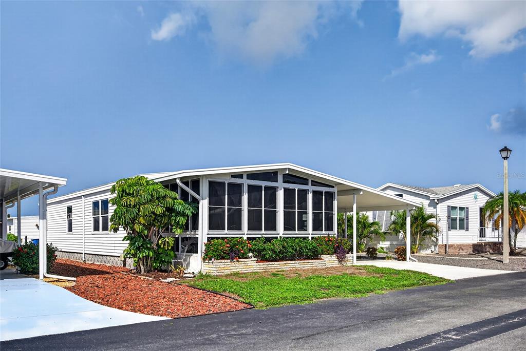 A white manufactured home features a large screened-in porch and a paved driveway — 11 DEL PRADO DRIVE, ENGLEWOOD, FL
