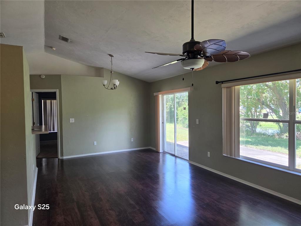 A living room features dark wood flooring, a vaulted ceiling, a ceiling fan, and sliding doors — 340 PINE BREEZE DRIVE, EDGEWATER, FL