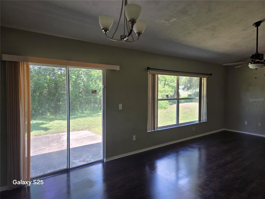 A living room features dark wood flooring, a sliding glass door, and a large window — 340 PINE BREEZE DRIVE, EDGEWATER, FL