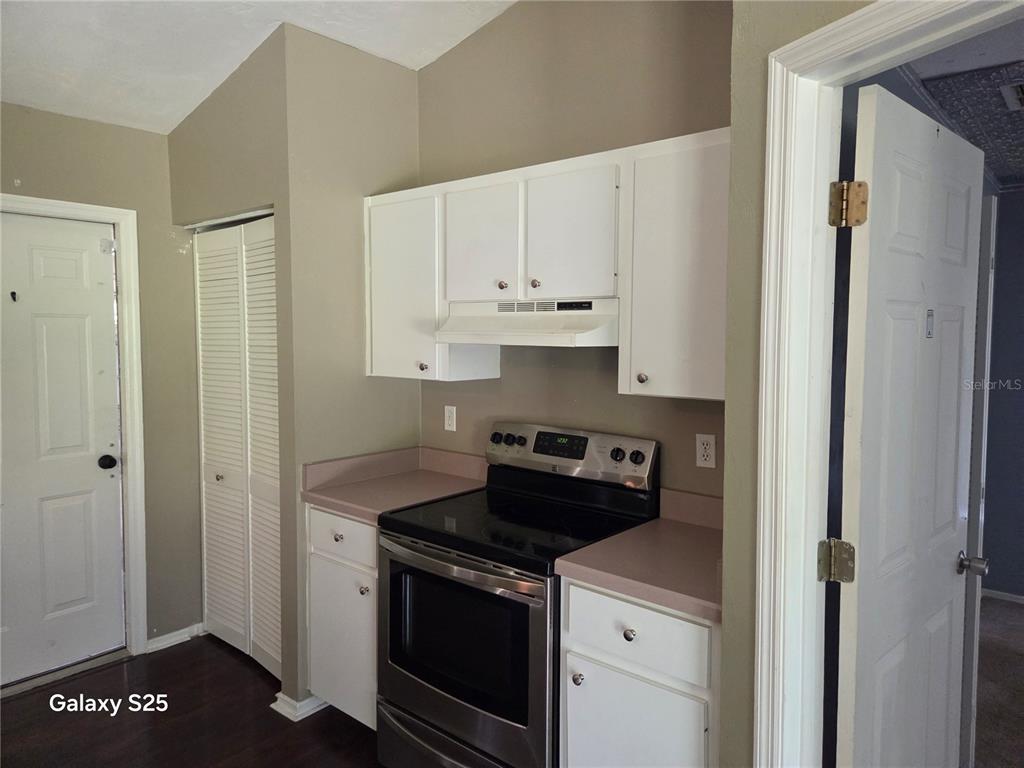 A kitchen features white cabinets, a stainless steel stove, and tan countertops — 340 PINE BREEZE DRIVE, EDGEWATER, FL