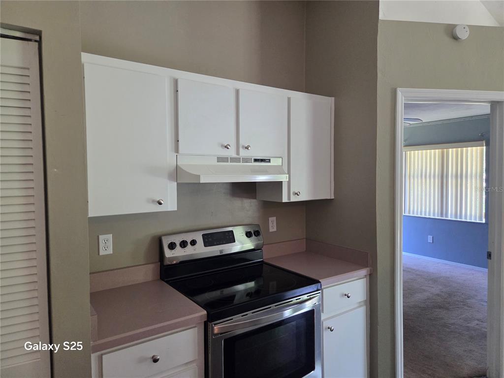 A kitchen features white cabinets, a stainless steel stove, and pink laminate countertops — 340 PINE BREEZE DRIVE, EDGEWATER, FL