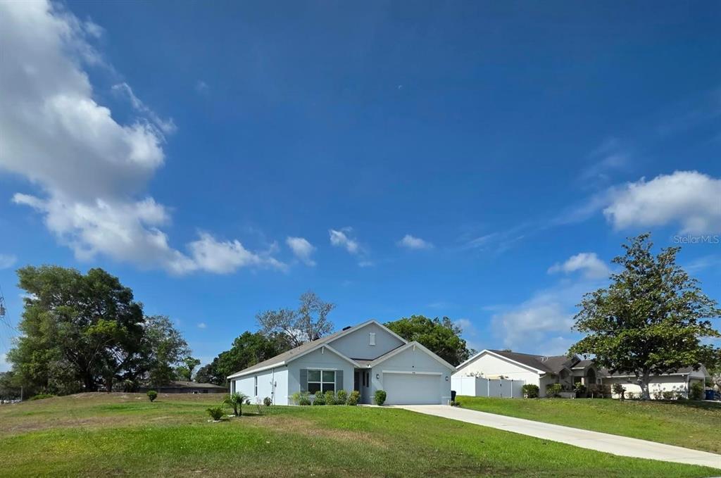 A single-story house with a light-colored exterior, a two-car garage, and a large front lawn — 4446 BAYRIDGE COURT, SPRING HILL, FL