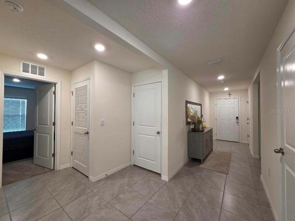 A tiled hallway features white doors, a louvered closet, and a gray console table — 4446 BAYRIDGE COURT, SPRING HILL, FL