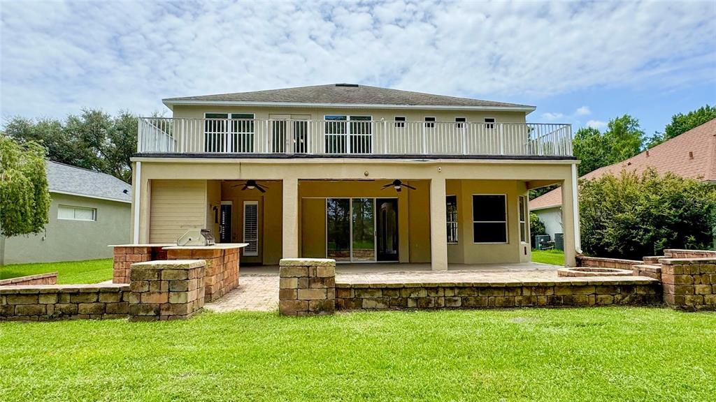 The exterior of a two-story house features a covered patio, stone walls, and a balcony — 14125 DEEP LAKE DRIVE, ORLANDO, FL