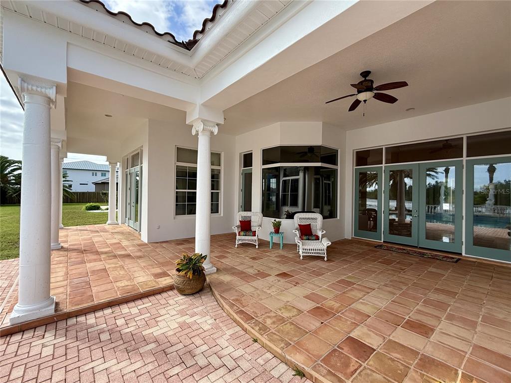 A covered outdoor patio features a dining set, lounge chairs, and an outdoor kitchen area — 660 LAMBERT AVENUE, FLAGLER BEACH, FL