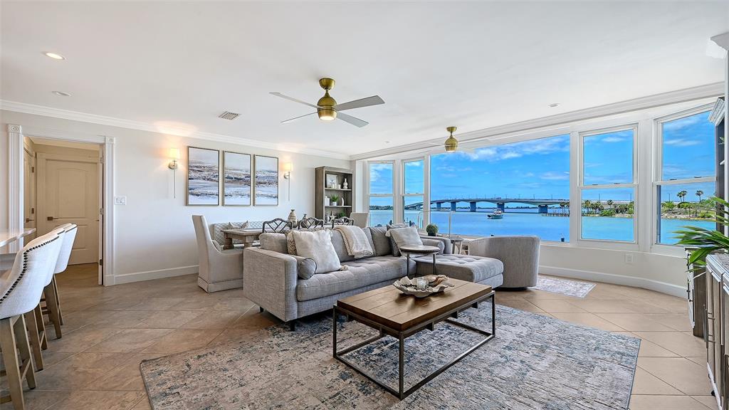 A living room features a gray sectional sofa, a coffee table, and large waterfront windows — 174 GOLDEN GATE POINT UNIT 22, SARASOTA, FL