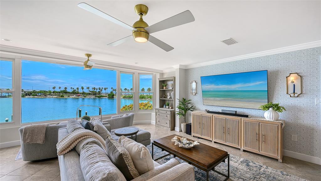 A living room features a large television, a sectional sofa, and a waterfront view — 174 GOLDEN GATE POINT UNIT 22, SARASOTA, FL