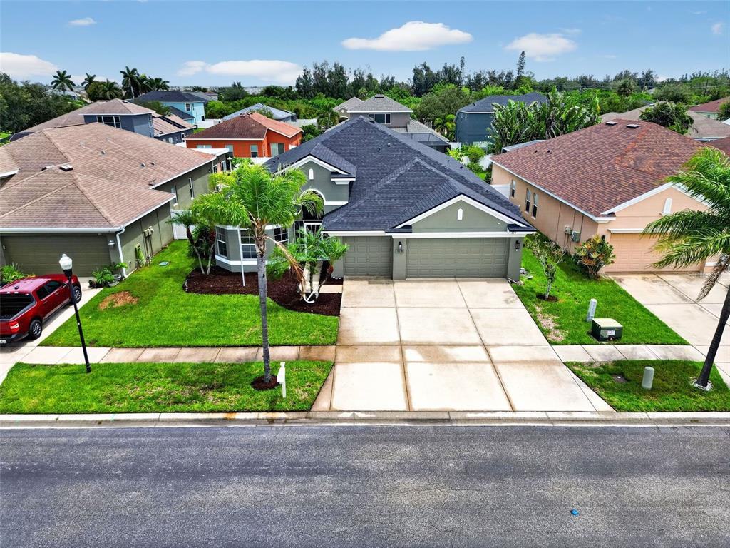 An aerial view shows a suburban house with a dark roof, garage, and front lawn — 319 19TH STREET NW, RUSKIN, FL