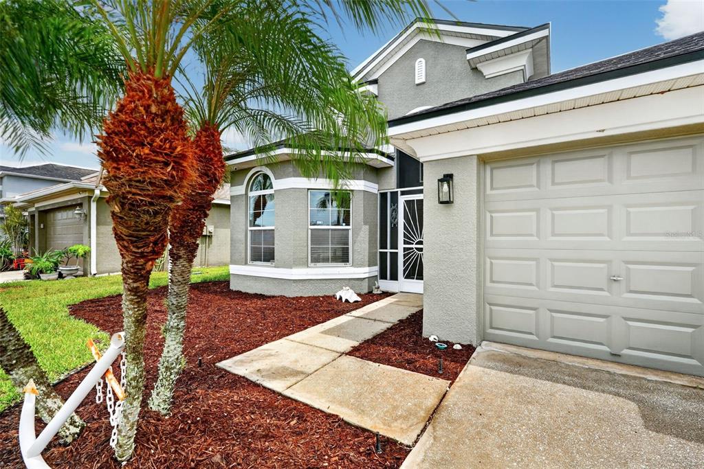 A gray house exterior features a two-car garage, a front walkway, and two palm trees — 319 19TH STREET NW, RUSKIN, FL