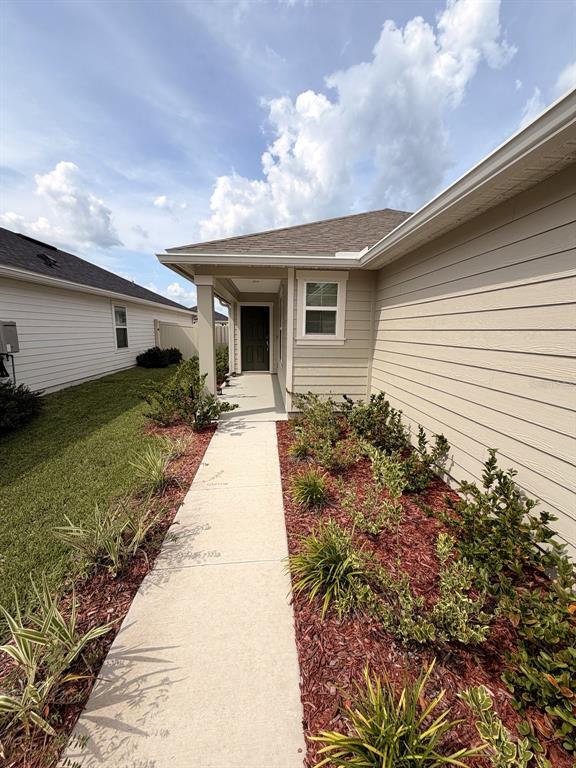 A concrete walkway leads to the front entrance of a tan house with horizontal siding — 354 BOULDER LANE, ST JOHNS, FL
