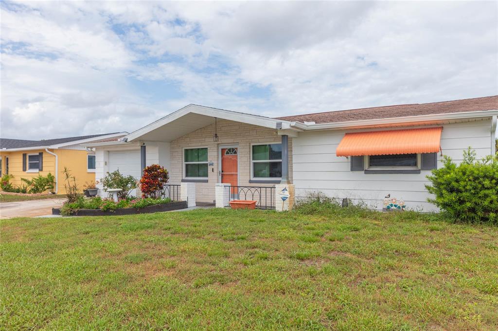A single-story house with white siding, a stone facade, and an orange window awning — 1447 WEYFORD LANE, HOLIDAY, FL
