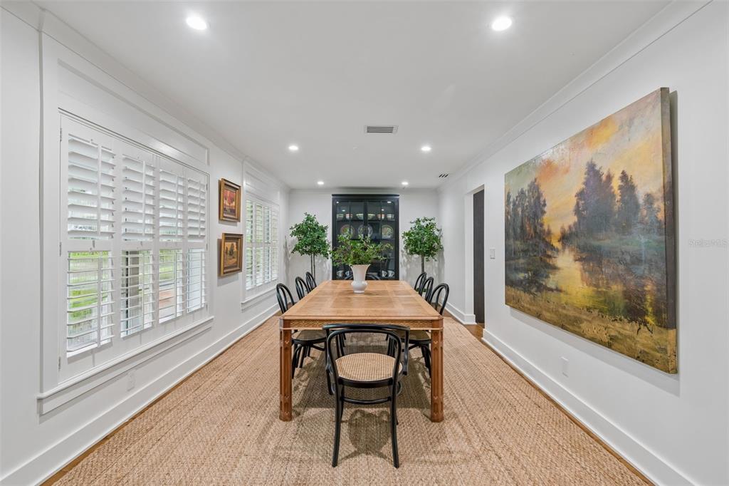 A dining room features a wooden table, black chairs, a large landscape painting, and shutters — 2807 W FOUNTAIN BOULEVARD, TAMPA, FL