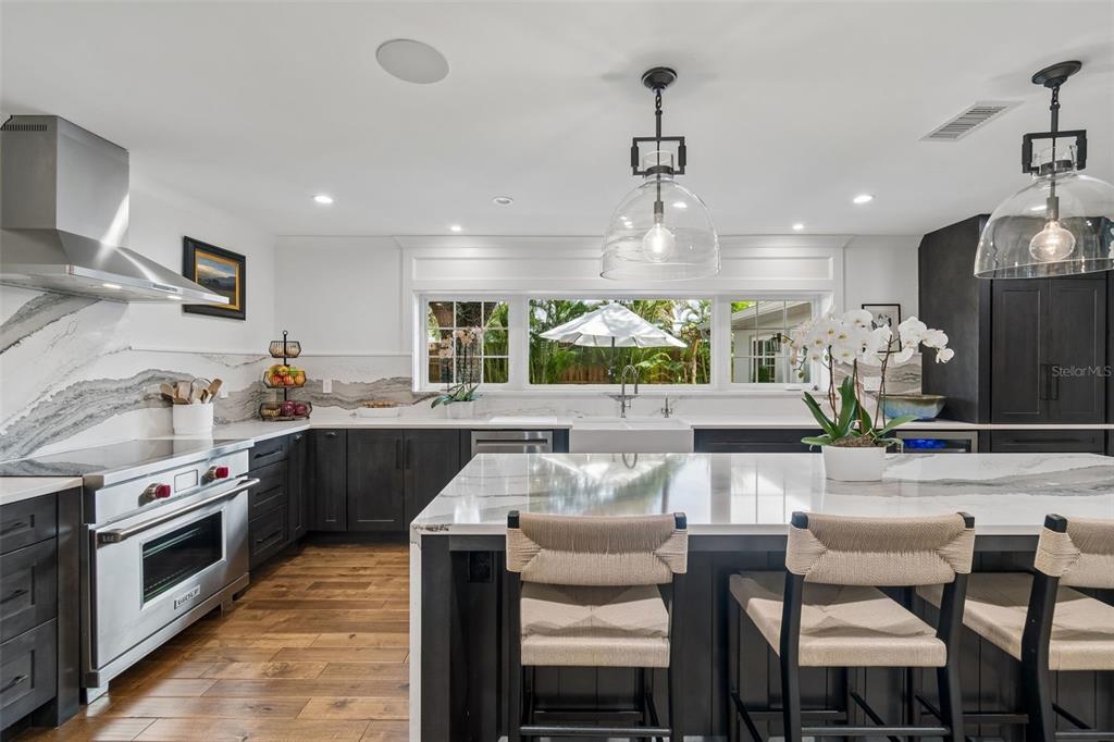 A modern kitchen features dark cabinetry, white marble countertops, a large island, and pendant lighting — 2807 W FOUNTAIN BOULEVARD, TAMPA, FL