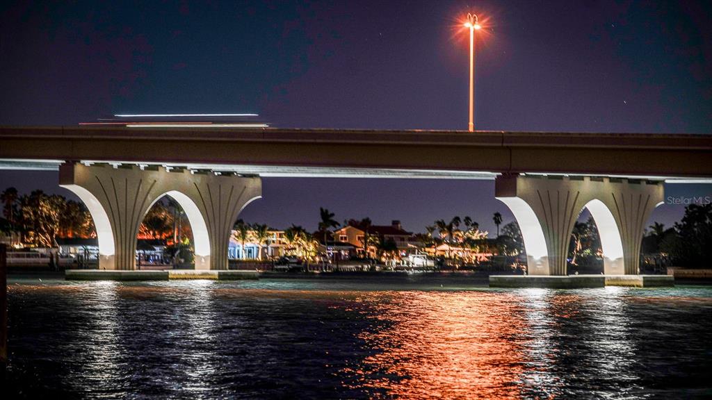A concrete bridge spans over a dark body of water at night under a streetlamp — 3606 BELLE VISTA DRIVE E, ST PETE BEACH, FL