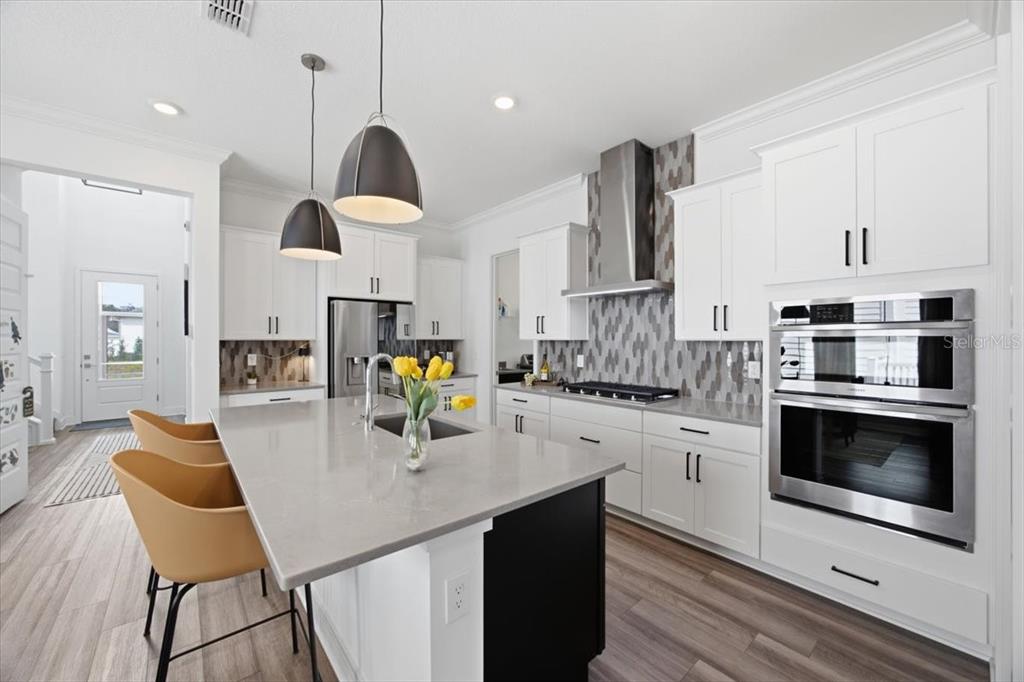 A modern kitchen features white cabinets, a gray quartz island, and stainless steel appliances — 226 HAMMOCK PRESERVE LOOP, OAKLAND, FL