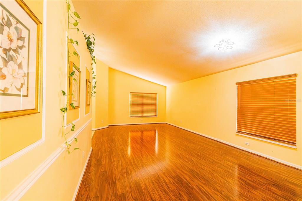 An empty room with yellow walls, wood-look flooring, and two windows with closed blinds — 1844 OXTON COURT, OCOEE, FL