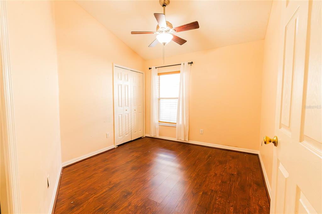 An empty bedroom features light-colored walls, dark wood-look flooring, a ceiling fan, and a closet — 1844 OXTON COURT, OCOEE, FL