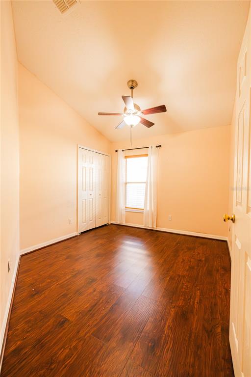A bedroom with dark wood flooring, a ceiling fan, a window with curtains, and a closet — 1844 OXTON COURT, OCOEE, FL