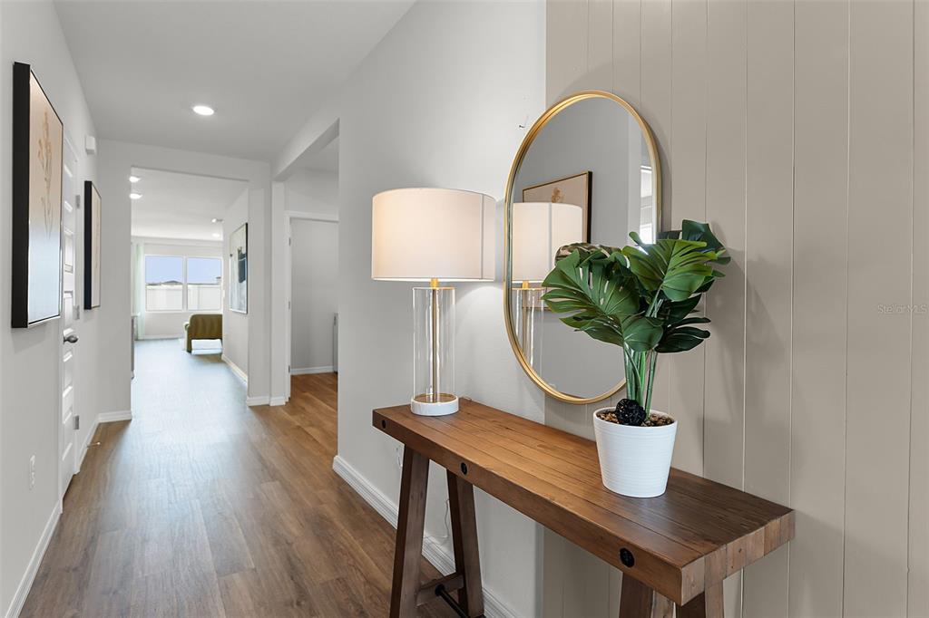 A hallway features wood-look flooring, a wooden console table with a lamp, and a round mirror — 2490 AVEENO AVENUE, HAINES CITY, FL