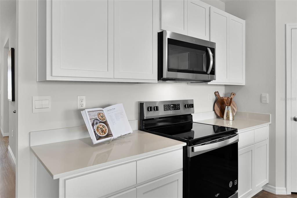 A modern kitchen features white cabinets, stainless steel appliances, and light-colored countertops — 2490 AVEENO AVENUE, HAINES CITY, FL