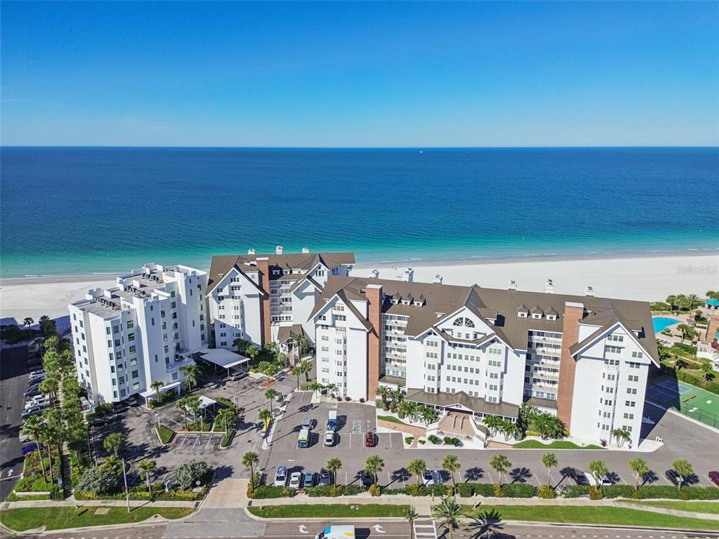 An aerial view shows a large white multi-story beachfront resort complex with a parking lot — 1586 GULF BOULEVARD UNIT 2103, CLEARWATER, FL