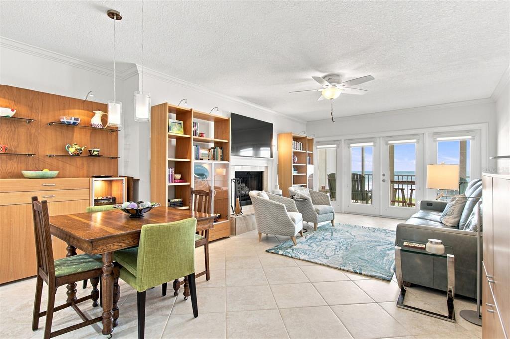 A living and dining area features a fireplace, built-in shelving, and a balcony with ocean views — 1586 GULF BOULEVARD UNIT 2103, CLEARWATER, FL