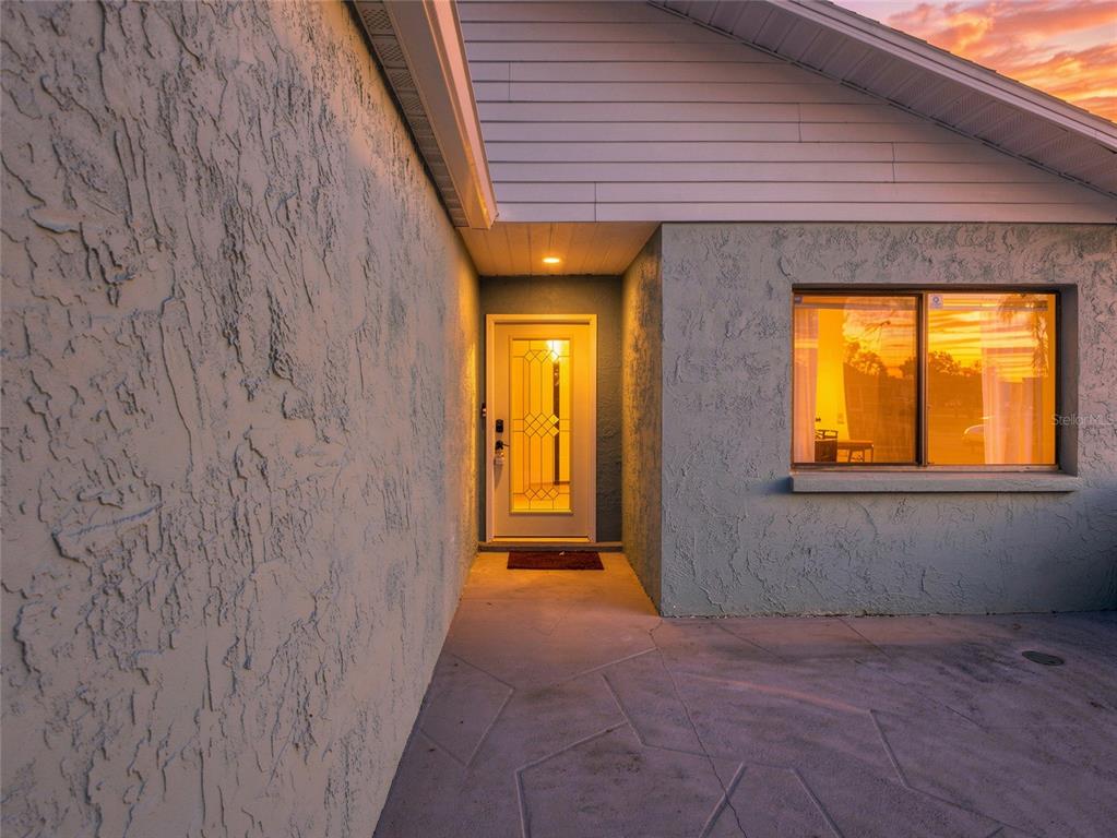 The exterior entrance features a textured stucco wall, a front door with glass inserts, and a window — 1644 PARAKEET COURT, MELBOURNE, FL