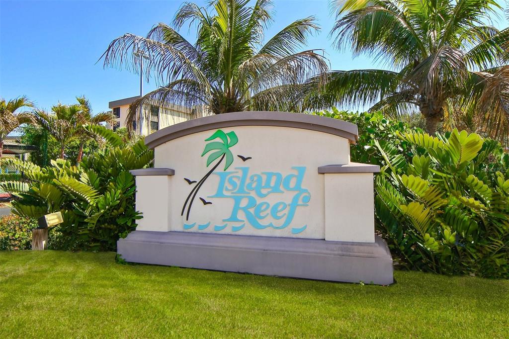 A sign for Island Reef stands in a grassy area surrounded by palm trees and bushes — 8770 MIDNIGHT PASS ROAD UNIT 302B, SARASOTA, FL