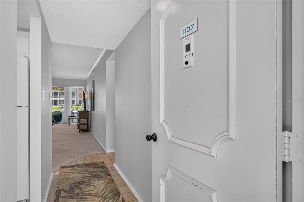A kitchen with white cabinets and tile floors is visible through an open doorway — 4390 EXETER DRIVE UNIT 107, LONGBOAT KEY, FL
