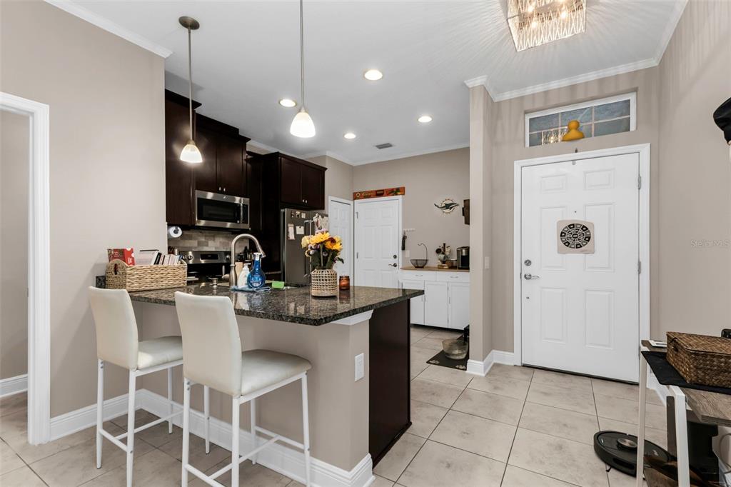 A kitchen features dark wood cabinets, a granite island with bar seating, and tile flooring — 7826 52ND TERRACE E, BRADENTON, FL