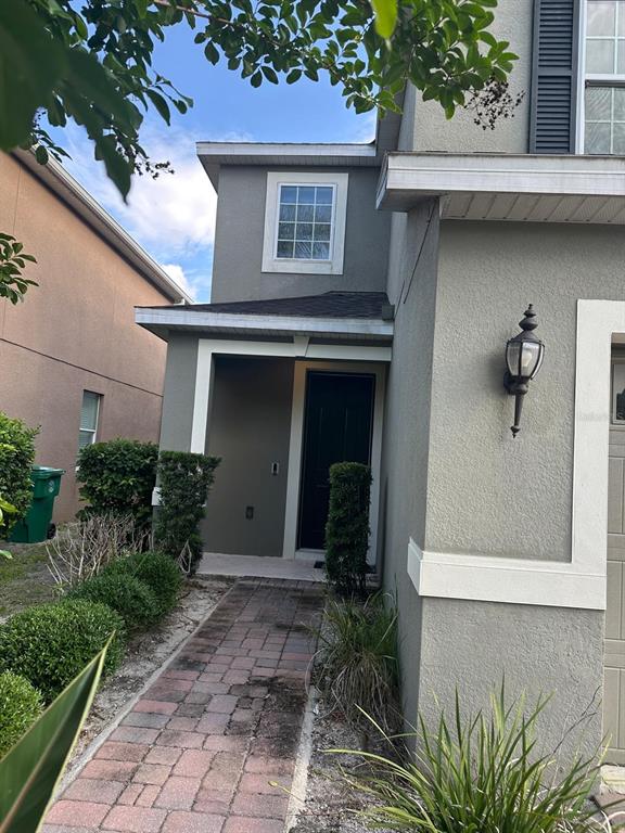 A paved walkway leads to the front entrance of a two-story gray stucco house — 1382 RILEY CIRCLE, DELAND, FL