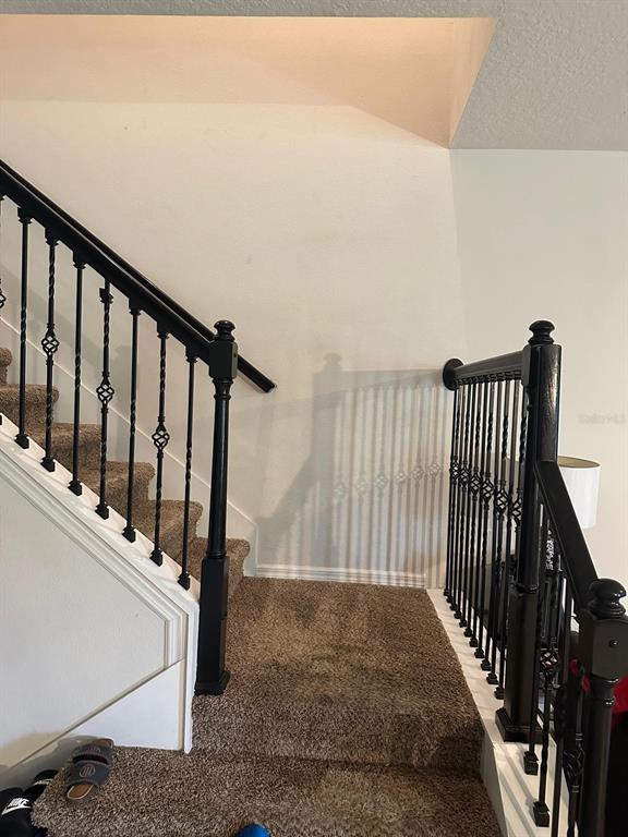 A carpeted staircase features black wooden posts and decorative metal balusters — 1382 RILEY CIRCLE, DELAND, FL