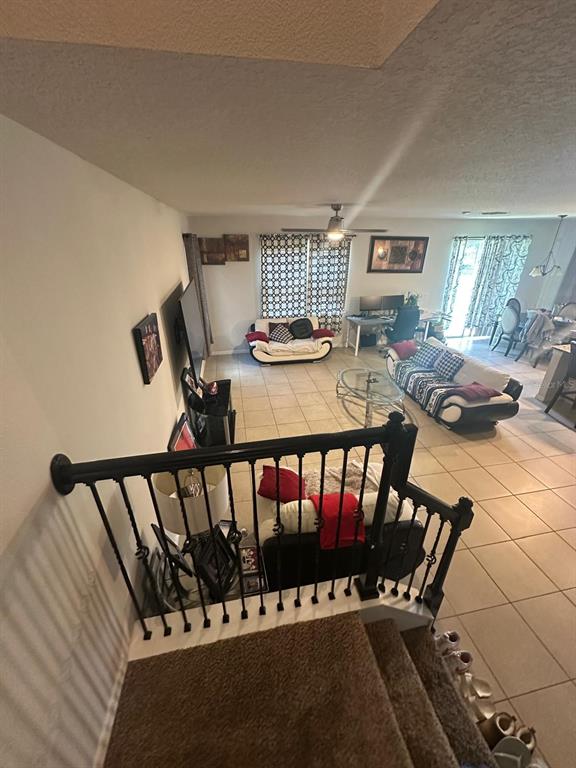 A high-angle view shows a living room with tile flooring, a staircase, and furniture — 1382 RILEY CIRCLE, DELAND, FL