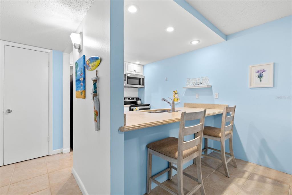 A kitchen with a breakfast bar, light blue walls, and two wooden stools — 12760 INDIAN ROCKS ROAD UNIT 107, LARGO, FL