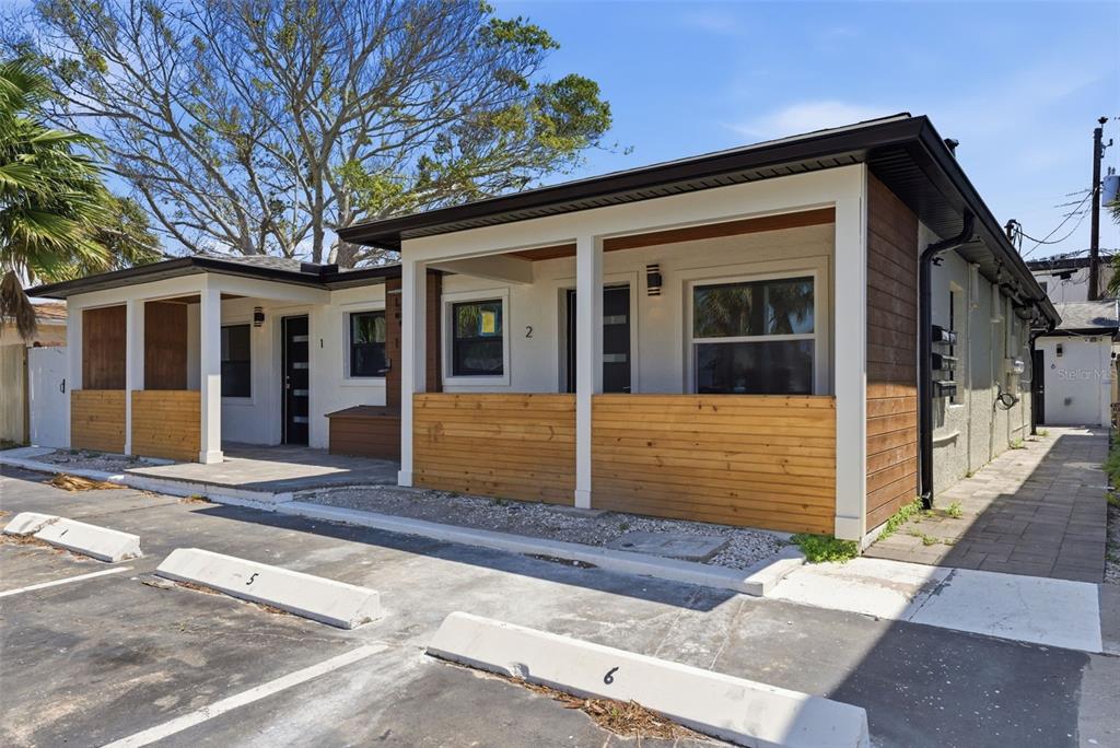 A low-rise apartment building with two numbered front entrances, wood-paneled porches, and paved parking — 113 145TH AVENUE E UNIT 2, MADEIRA BEACH, FL