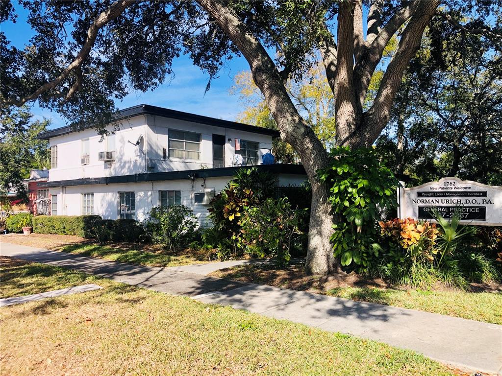 A two-story white building with a flat roof stands behind a large tree and sign — 1762 N FORT HARRISON AVENUE, CLEARWATER, FL