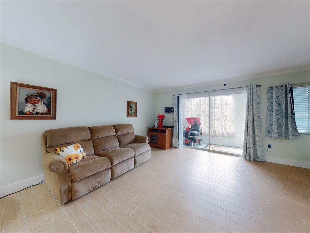 A living room features light tile flooring, a brown sofa, and sliding glass doors to a patio — 588 BAHIA CIRCLE UNIT A, OCALA, FL
