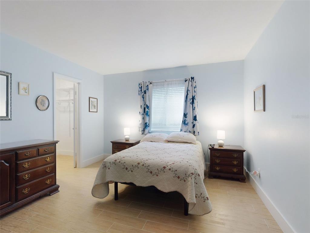A bedroom with light blue walls, tile flooring, a bed, two nightstands, and a closet — 588 BAHIA CIRCLE UNIT A, OCALA, FL