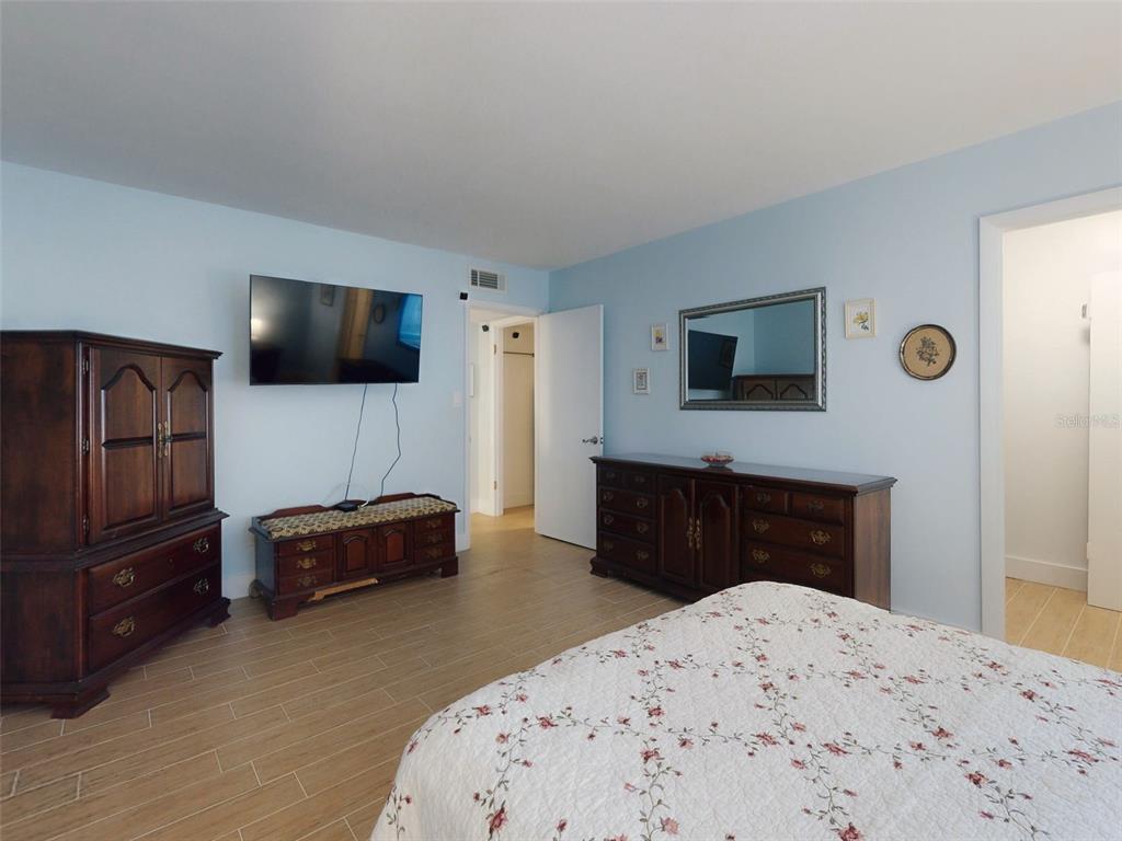 A bedroom with light blue walls, wood-look tile flooring, and two dark wood dressers — 588 BAHIA CIRCLE UNIT A, OCALA, FL
