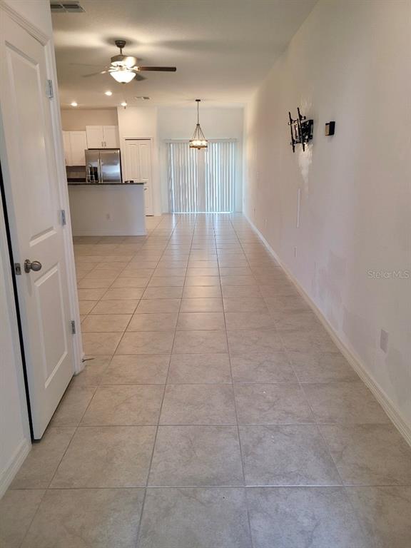 A tiled living area leads to a kitchen with stainless steel appliances and sliding glass doors — 5122 FORUM BOULEVARD, HOLIDAY, FL