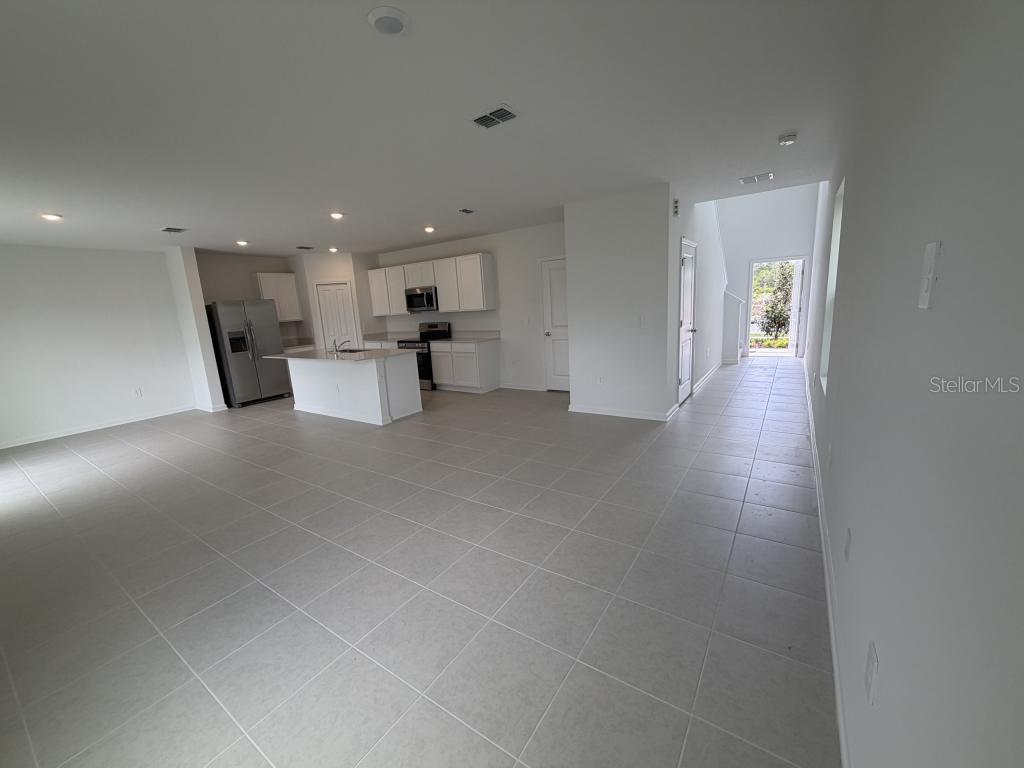 An open-concept kitchen and living area features white cabinets, a center island, and tile flooring — 2510 HALLOW GRADEN RD, EUSTIS, FL