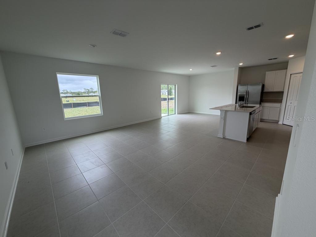 An open-concept living area with tile flooring, a kitchen island, and a sliding glass door — 2510 HALLOW GRADEN RD, EUSTIS, FL
