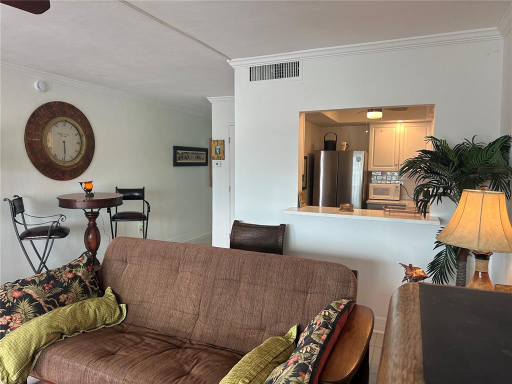 A living room with a brown futon, a small dining table, and a kitchen pass-through window — 6161 GULF WINDS DRIVE UNIT 150, ST PETE BEACH, FL