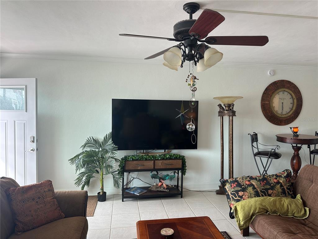 A living room features a ceiling fan, a wall-mounted television, and tile flooring — 6161 GULF WINDS DRIVE UNIT 150, ST PETE BEACH, FL