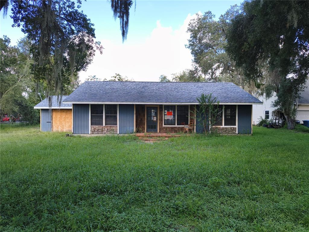 A single-story house with blue vertical siding and stone accents sits on a grassy lot — 5125 LAKEWOOD DRIVE, DADE CITY, FL