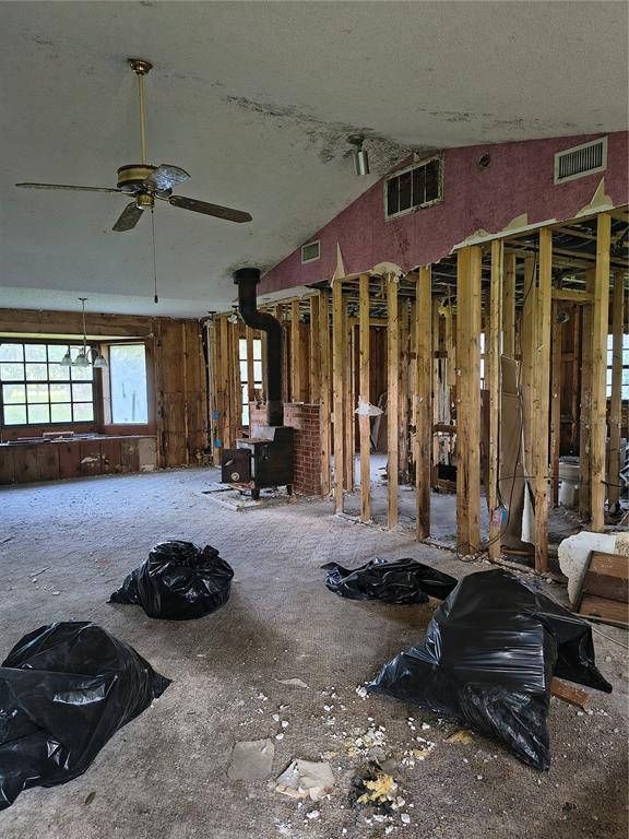A room under renovation features exposed wall studs, a wood-burning stove, and a ceiling fan — 5125 LAKEWOOD DRIVE, DADE CITY, FL