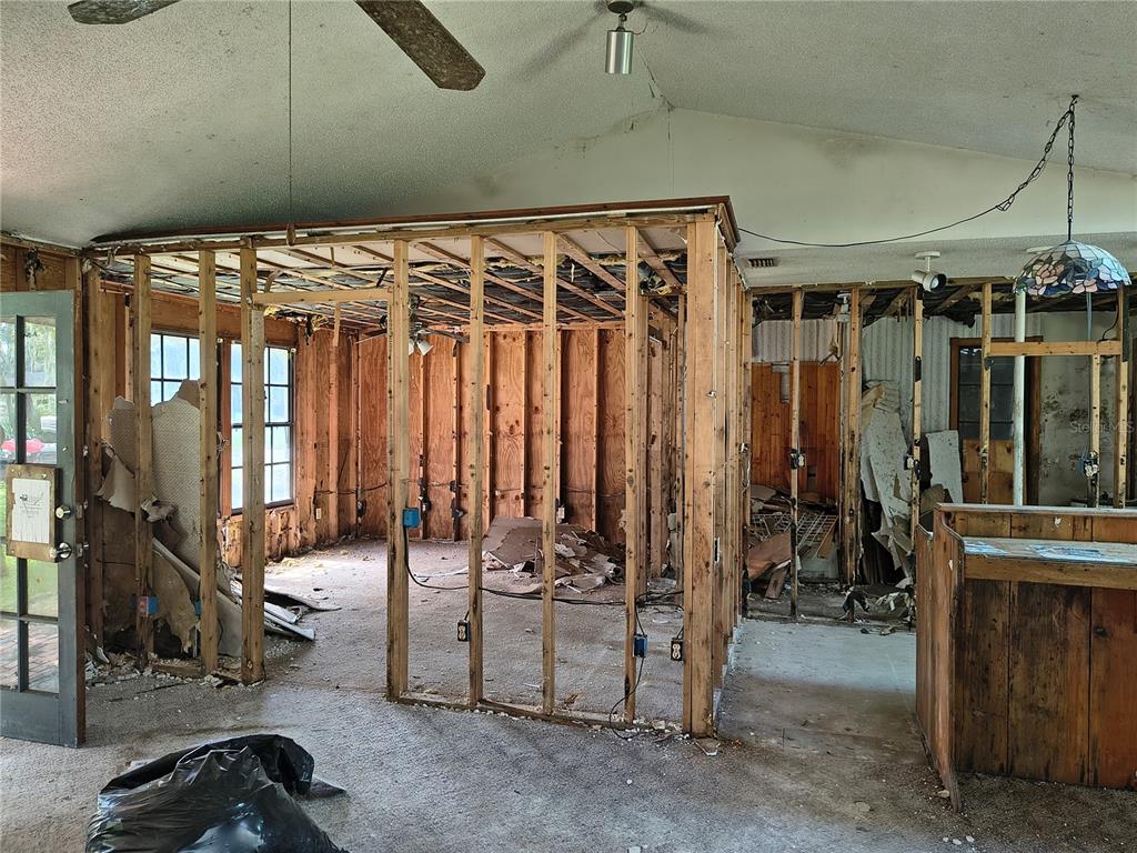 An interior view of a room undergoing renovation with exposed wall studs and debris — 5125 LAKEWOOD DRIVE, DADE CITY, FL