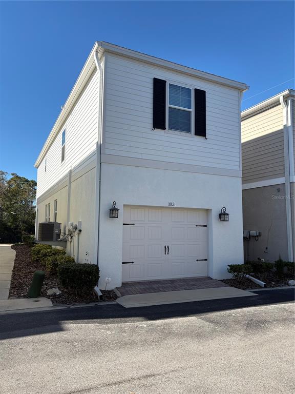 A two-story house exterior features a white garage door, siding, and a single upper window — 103 CUTLASS WAY, OLDSMAR, FL